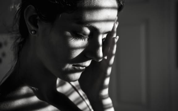 Depressed woman near window at home.