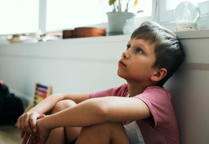 A boy day dreaming alone in a room.