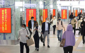 Commuters in Fukuoka City pass electronic billboards calling for the prevention of the spread of Covid-19.