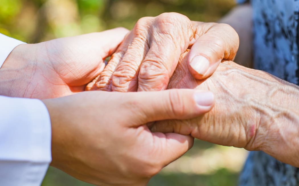 Close up medical doctor holding elderly female's trembling hands