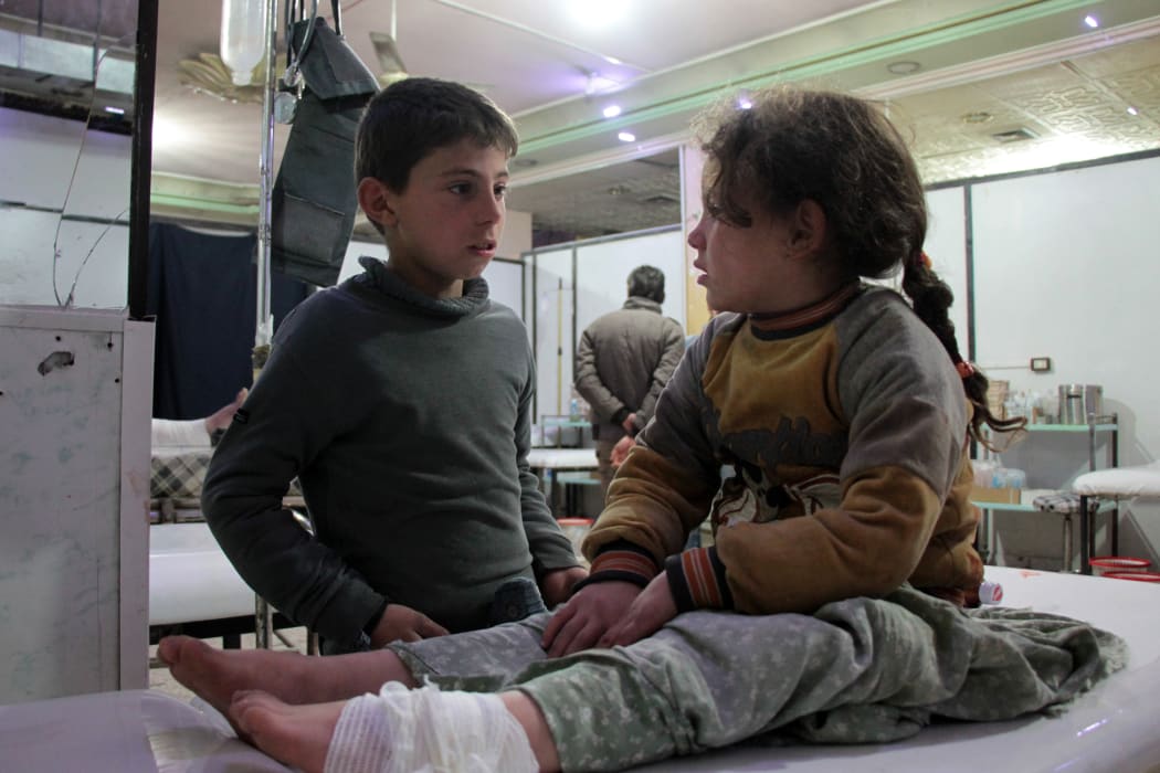 A Syrian boy talks to an injured girl as she lies on an operating bed in an emergency room in the rebel-held town of Douma in Syria's eastern Ghouta region on December 17.