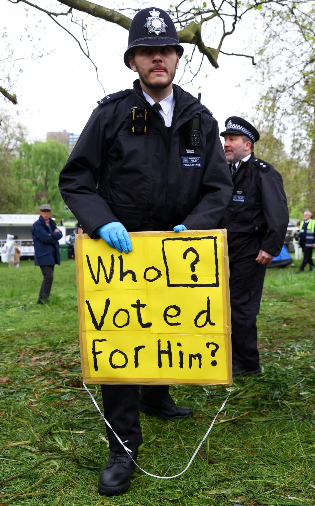 A police officer holds a placard taken from an anti-monarchy protester as people gather at the Mall on the day of the coronation of Britain's King Charles III and Queen Camilla, in London, on May 6, 2023. - The set-piece coronation is the first in Britain in 70 years, and only the second in history to be televised. Charles will be the 40th reigning monarch to be crowned at the central London church since King William I in 1066. Outside the UK, he is also king of 14 other Commonwealth countries, including Australia, Canada and New Zealand. Camilla, his second wife, will be crowned queen alongside him and be known as Queen Camilla after the ceremony. (Photo by PAUL CHILDS / POOL / AFP)