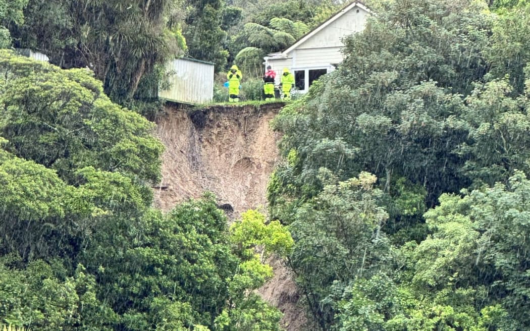 Emergency workers inspect house where part of hillside has slipped away - Hutt Valley