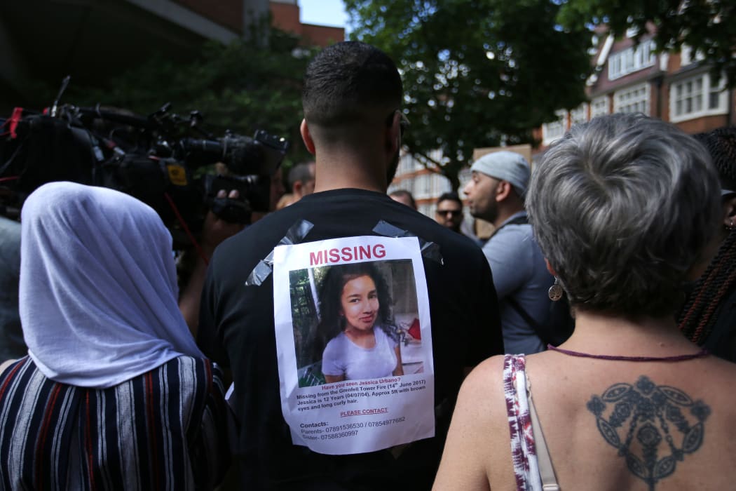 A man carries a picture of a missing person on his back, during a protest outside Kensington Town Hall, London.