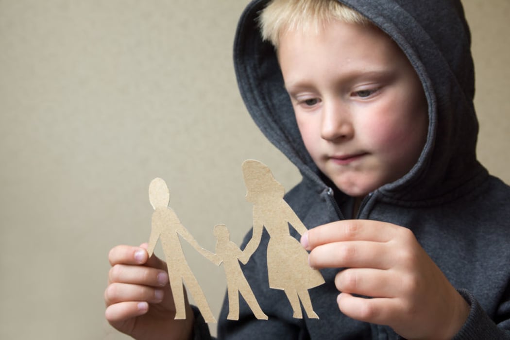 A photo of a boy with a paper cut out family holding hands