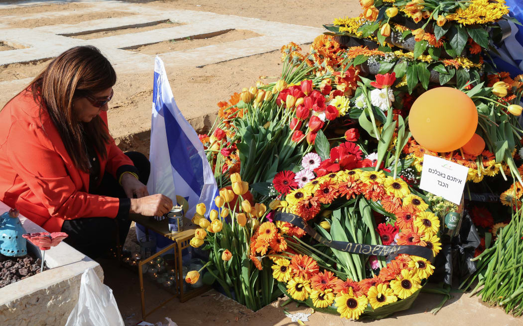 Mourners light candles at the cemetery for the funeral of the Bibas' at Zohar near kibbutz Nir Oz in southern Israel on February 26, 2025. Thousands of mourners, carrying flags and orange balloons, joined the funeral procession on February 26 for Shiri Bibas and her two sons, who were among the hostages taken by Palestinian militants in Gaza in October 2023, and died during their captivity. Their bodies were returned to Israel on February 20 as part of an ongoing ceasefire agreement that has halted the war in Gaza.