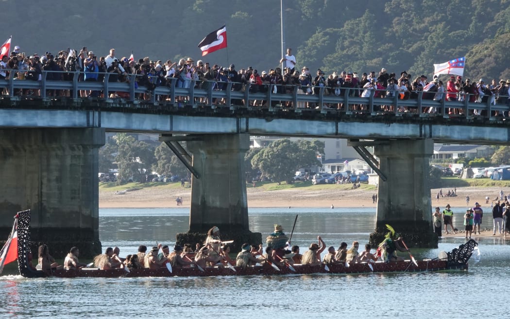 A waka passes a crowd of spectators on Waitangi Bridge. Photo: RNZ / Peter de Graaf