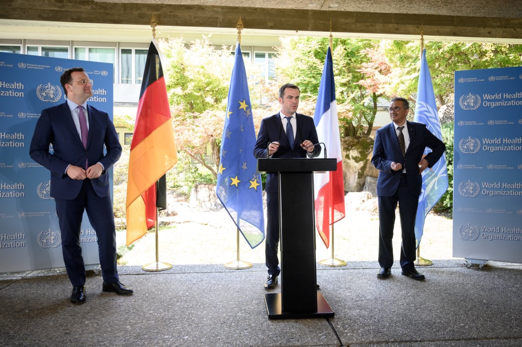 French Health Minister Olivier Veran speaks, flanked by German Health Minister Jens Spahn (left), and WHO Director-General Tedros Adhanom Ghebreyesus.