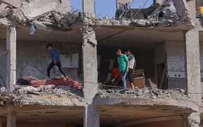 Palestinians inspect a building, destroyed by Israeli strikes, in Beit Hanun in the northern Gaza Strip on May 21, 2021.