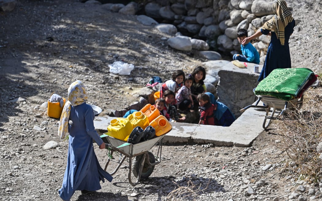 An Afghan woman carries a wheelbarrow while going for water to a fountain in a village in Qarabagh district distant 56 km to the south-west of Ghazni, in Ghazni province, on 14 November, 2021.