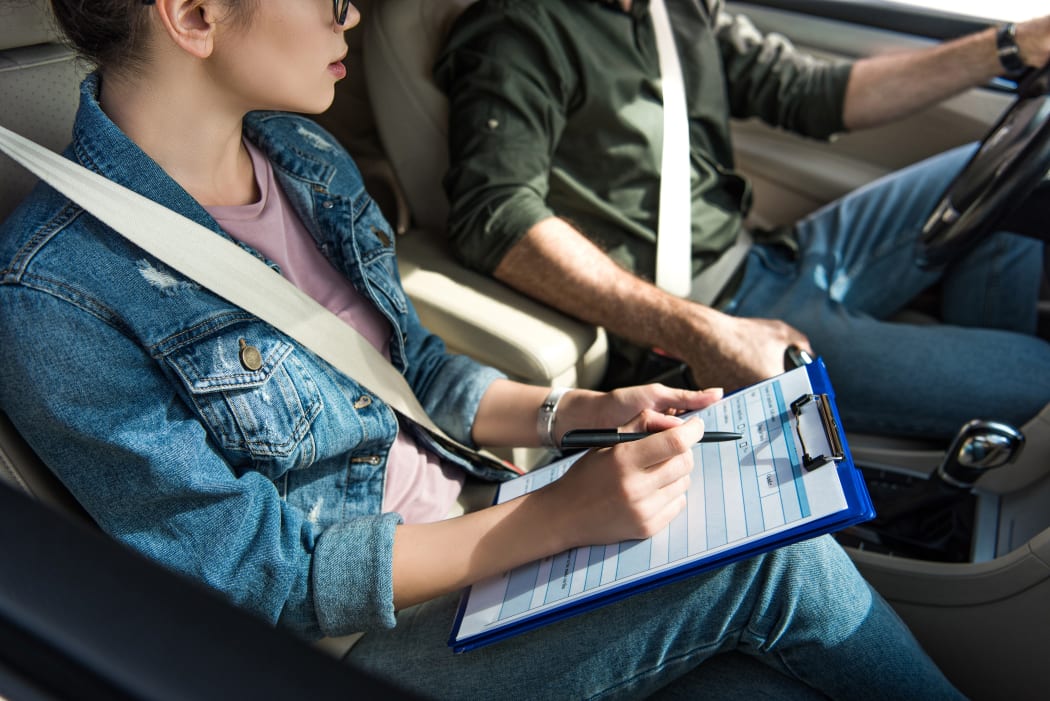 cropped image of student and teacher in car at driving test