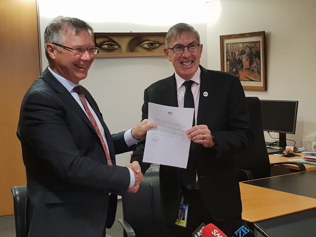 Trade Minister David Parker receiving a note from the Australian High Commissioner Ewen McDonald confirming Australia's ratification.