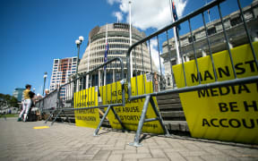 Signs from protestors sit outside Parliament during the apology for abuse in state care