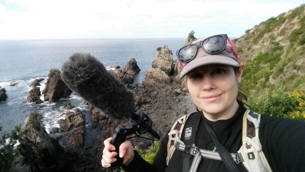 Michelle Roper on bird recording field work on an offshore island. She is holding a microphone.