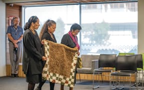 Te Papa Tongarewa kaimahi Lisa Osborne and Moana Parata with Tūhoe kuia Lucy Hona carry the kahu huruhuru which was stolen from prophet Rua Kēnana’s daughter Pinepine in a police raid over 100 years ago.