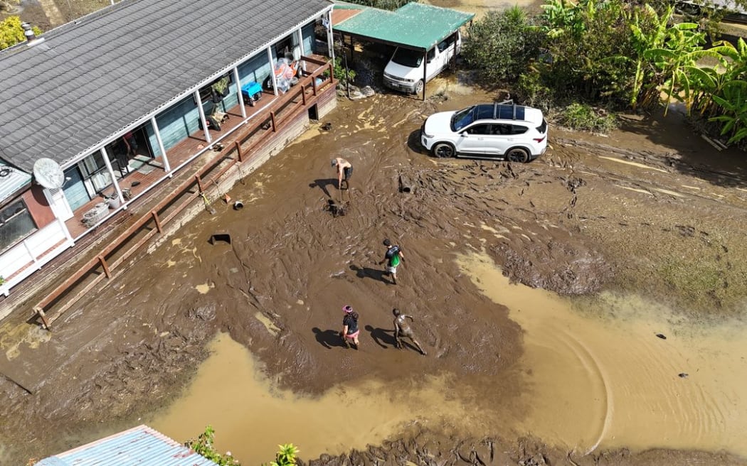 A family begins the enormous task of shovelling silt off their Whirinaki property.