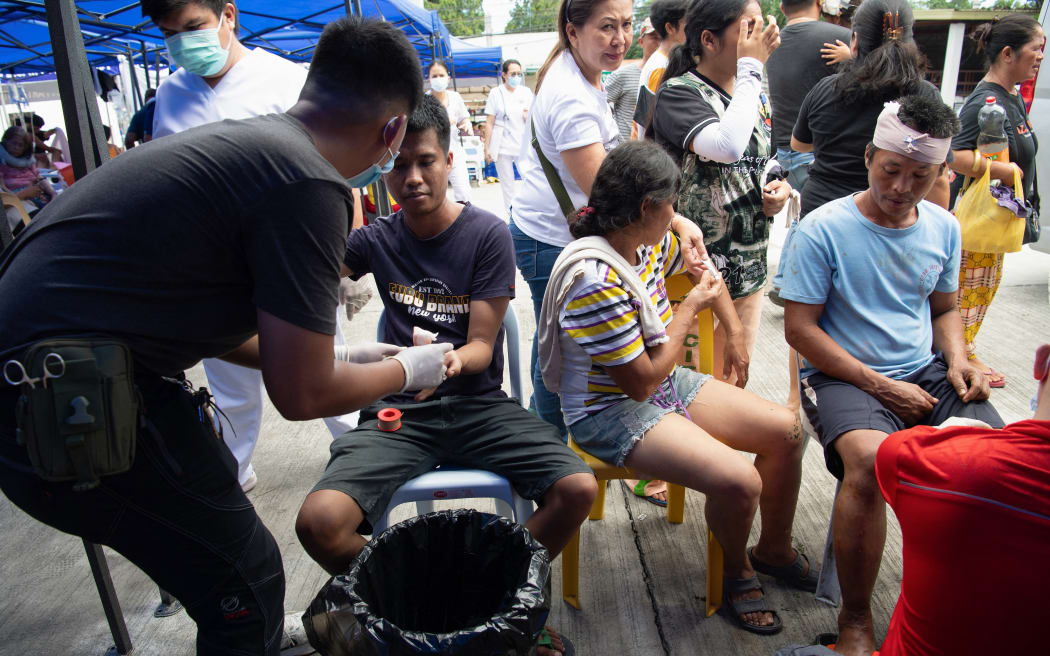 Injured people receive treatment at a makeshift emergency station outside the provincial hospital in Bogo City on October 1, 2025, after a powerful 6.9 magnitude earthquake jolted the central Philippines, killing dozens on the island of Cebu with fears the toll could rise. The death toll from a powerful earthquake in the central Philippines approached 60 on October 1, with injured patients overwhelming hospitals on the island of Cebu as workers carried dozens of body bags away in the chaotic aftermath. (Photo by Ted ALJIBE / AFP)