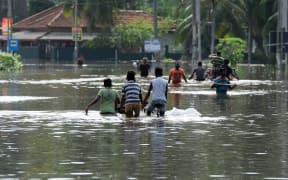 Sri Lankan residents look on from a shop surrounded by floodwaters in Nagoda in Kalutara district.