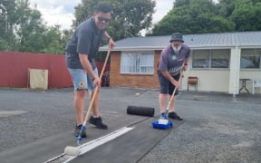 NPDC chief executive Gareth Green repainting parking marking at the council-owned List St pensioner flats with Councillor Sam Bennett.