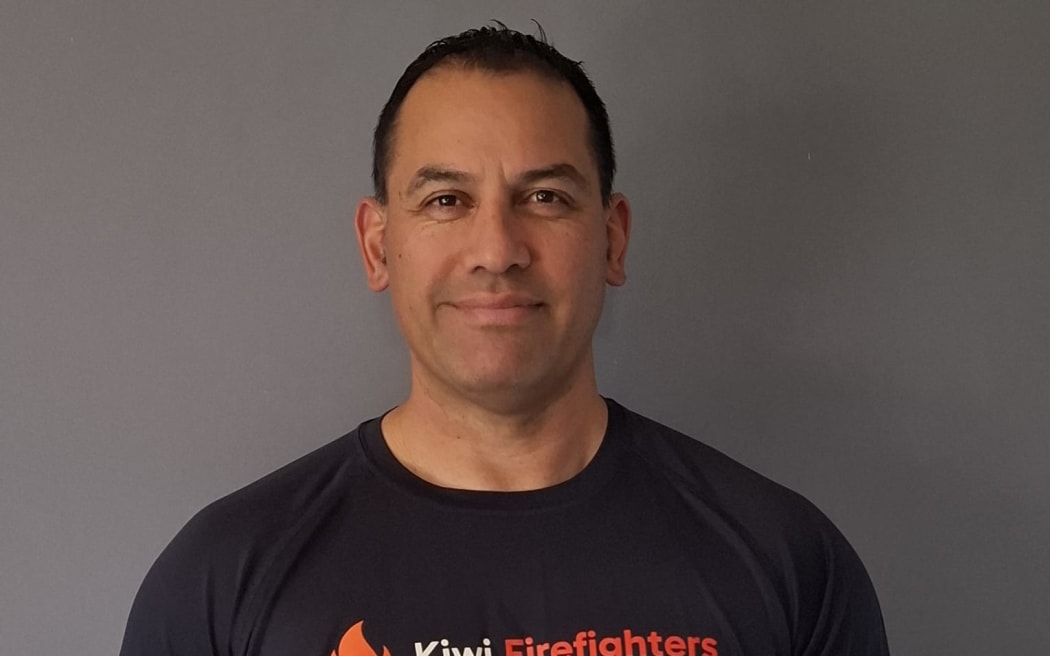 This is a headshot of Bevin holding a copy of the 2026 Kiwi Firefighters calendar.