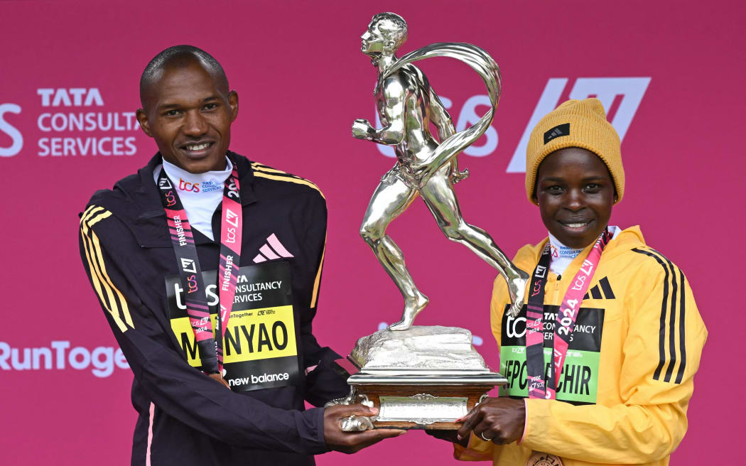 Winners of the men's and women's races, Kenya's Alexander Mutiso Munyao (L) and Kenya's Peres Jepchirchir (R) pose with the trophy at the presentations for the 2024 London Marathon in central London on April 21, 2024. (Photo by JUSTIN TALLIS / AFP) / “Restricted to editorial use - sponsorship of content subject to LMEL agreement”.