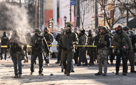 Federal agents stand near police tape as demonstators gather near the site of where state and local authorities say a man was shot by federal agents earlier in the morning in Minneapolis, Minnesota, on January 24, 2026. Minnesota Governor Tim Walz said Saturday that federal agents deployed in Minneapolis as part of a sweeping immigration crackdown had carried out "another horrific shooting," less than three weeks after the fatal shooting of Renee Good. (Photo by ROBERTO SCHMIDT / AFP)