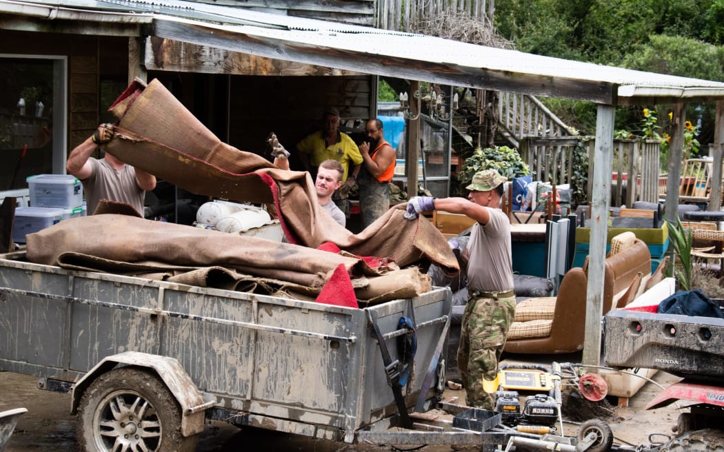 NZDF personnel help throw out sodden belongings at a Tinui property after Cylcone Gabrielle.