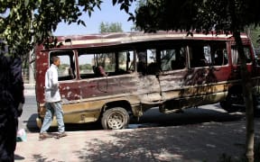 A boy walks past the wreckage of a bus following a suicide bombing in Kabul.