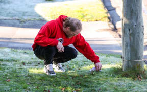 Nate Light, friend of man critically shot by police in Christchurch, lays flowers down.