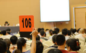 People holding auction paddle to buy from auction.
