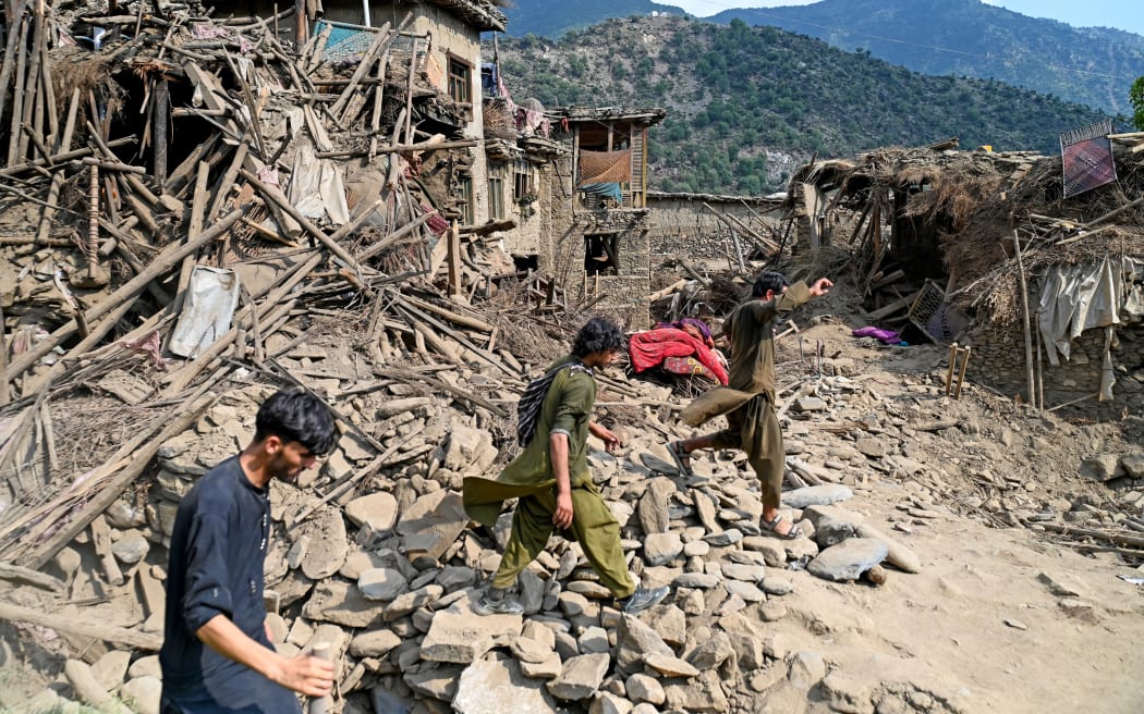 EDITORS NOTE: Graphic content / Afghans walk past damaged houses, after earthquakes at Mazar Dara village in Nurgal district, Kunar province, in Eastern Afghanistan, on September 1, 2025. More than 800 people have died and over 2,700 were injured from August 31 night to September 1, 2025, in eastern Afghanistan after a 6-magnitude earthquake, followed by at least five aftershocks felt hundreds of kilometers away. (Photo by Wakil Kohsar / AFP)