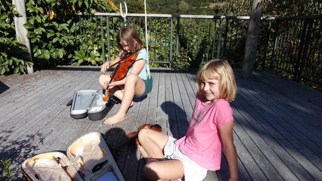 Isabelle and Sophie play their violins to attract the tui which seems to work