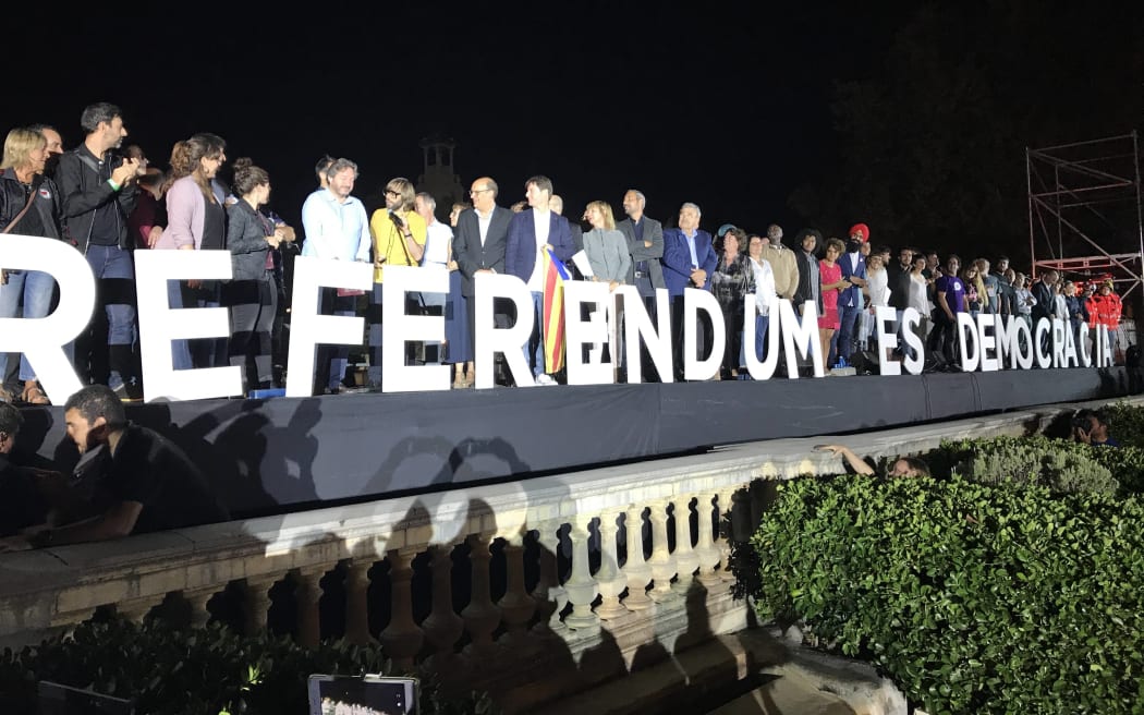 People stand behind a sign translating "Referendum Is Democracy" during the closing meeting of the Catalan pro-independence groups and political parties that campaign for 'Yes' in the October 1 referendum on self-determination in Catalonia, at Montjuic fairground in Barcelona, Spain.
