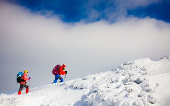 Two girls go on a snowy hill during a mountaineering adventure in the mountains.