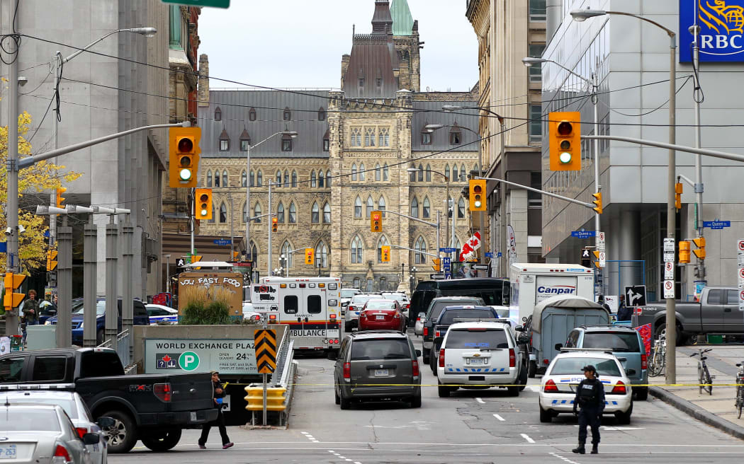 Police stand guard near the Gothic parliament building in Ottawa after yesterday's shooting.