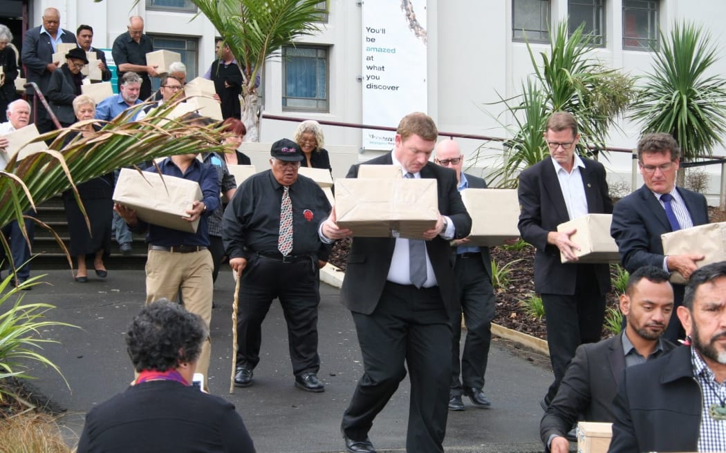 Carrying the kōiwi to the hearse for transport to the Aramoho Cemetery.