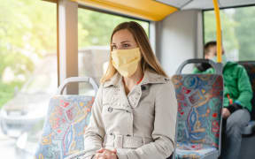 Woman using public transport during Covid-19 crisis wearing face mask.
