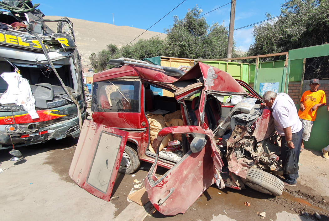 A man looks inside a minivan after it was crashed by a double-decker bus on the Pan American Highway in the Arequipa region.