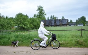Paramedic Nadezhda Konanava, 65, wearing a protective suit rides her electric bike at the village of Novaya Obo.