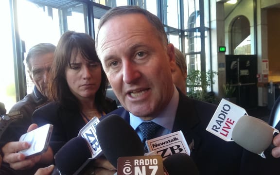 John Key with reporters.