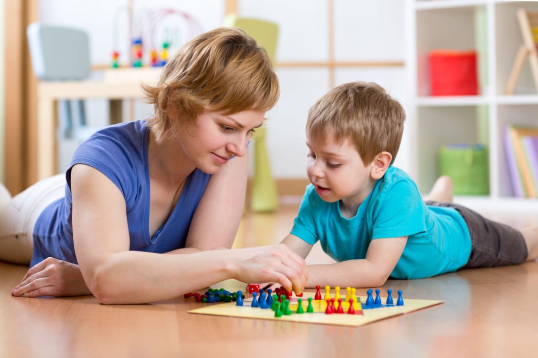 A photo of a mother and son lying on the floor playing a game