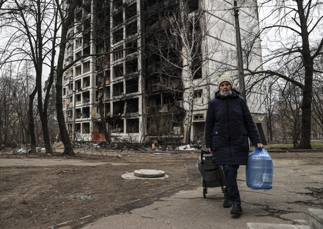 A woman  walks past a destroyed building after Russian shelling in Sviatoshinsky district of Kyiv, Ukraine on 30 March 2022.