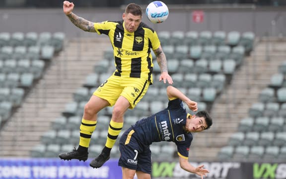 Gary Hooper of the Phoenix heads the ball over Cy Goddard of the Mariners during the A-League match