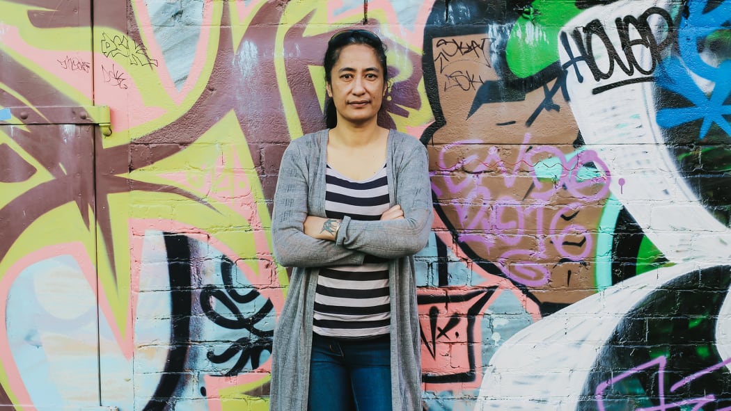 Portrait of Regina Tito standing against a wall