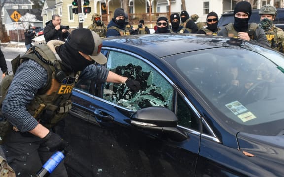 A federal officer breaks a car window as they begin the process of removing a woman from her vehicle near an area where ICE was operating in Minneapolis, Minnesota, on January 13, 2026. Hundreds more federal agents were heading to Minneapolis, the US homeland security chief said on January 11, brushing aside demands by the Midwestern city's Democratic leaders to leave after an immigration officer fatally shot a woman protester. In multiple TV interviews, US Homeland Secretary Kristi Noem defended the actions of the officer who shot and killed 37-year-old Renee Nicole Good, whose death has sparked renewed protests nationwide against President Donald Trump's immigration crackdown. (Photo by Octavio JONES / AFP) / ALTERNATE CROP