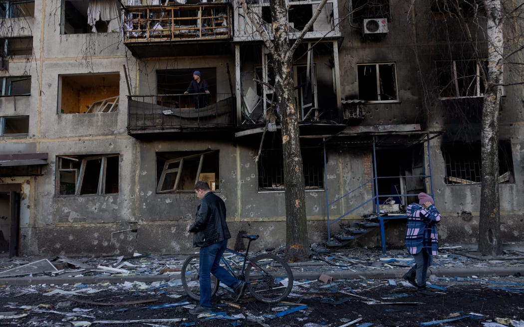People walk by a damaged residential building following a strike in Dobropillia, Donetsk region, on March 8, 2025, amid the Russian invasion of Ukraine. At least 11 people were killed and 30 wounded in Russian strikes on eastern Ukraine's Donetsk region late March 7, the country's emergency service said, raising the earlier death toll of four. "In the evening, Russians struck the centre of Dobropillia. At least 11 people were killed and 30 others were wounded," the service wrote in a post on Telegram, adding that at least nine buildings were damaged. (Photo by Tetiana DZHAFAROVA / AFP)