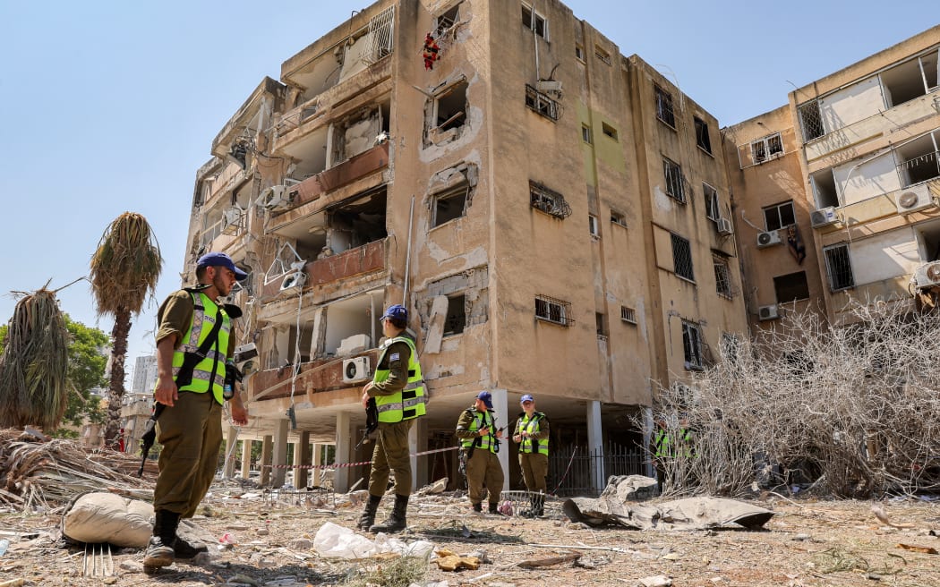Israeli security forces gather outside a building that was hit by an Iranian missile in Israel's central city of Holon on June 19, 2025. A hospital in southern Israel and two towns near Tel Aviv were struck after a barrage of Iranian missiles early on June 19, with rescuers reporting at least 47 people injured in the latest attacks. (Photo by Jack GUEZ / AFP)
