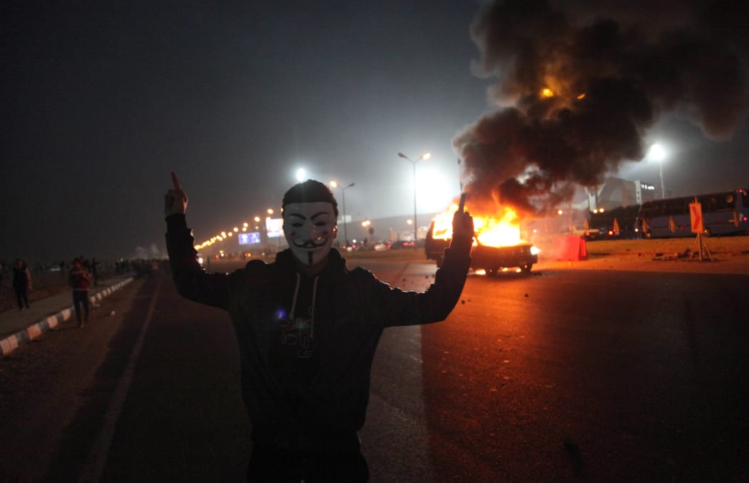 A man gestures near a burning car during clashes between Zamalek football club supporters and security forces on 8 February 2015.