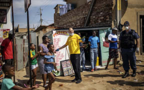 Activist Yusuf Abramjee (C) distributes soap bars amid concerns over the spread of Covid-19 coronavirus during a volunteer drive in the densely populated Diepsloot township in Johannesburg, South Africa.