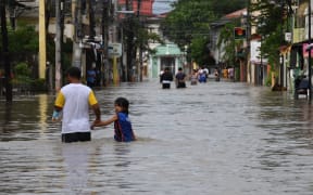 Residents wade through a flooded street as they head home after they were stranded overnight in Kawit town, Cavite province on 30 October 2022, a day after Tropical Storm Nalgae hit.